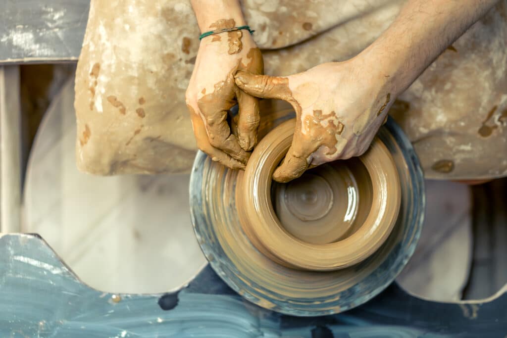 Mains d'un céramiste façonnant un vase en terre sur le tour de potier