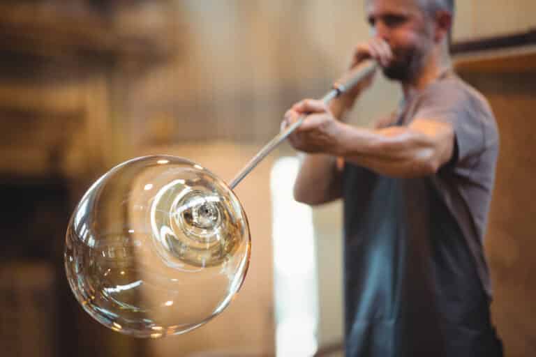 Souffleur de verre façonnant une pièce de verre en fusion au bout de sa canne