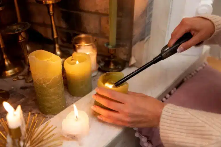 Bougies, encens et qualité de l’air intérieur : ce que disent les études - Ameublement et décoration, Astuces, DIY & Maison - Artisanat d'art Main allumant des bougies avec un briquet allume-feu sur une cheminée